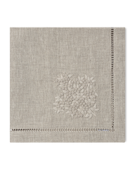 A natural linen napkin with a hemstitch border and natural french knot floral embroidery