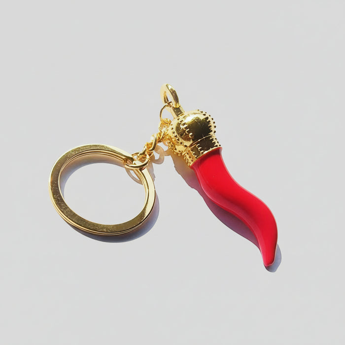 Keychain with red horn-like charm and gold accents on a white background