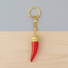 Red keychain with gold crown and gold ring on a white background