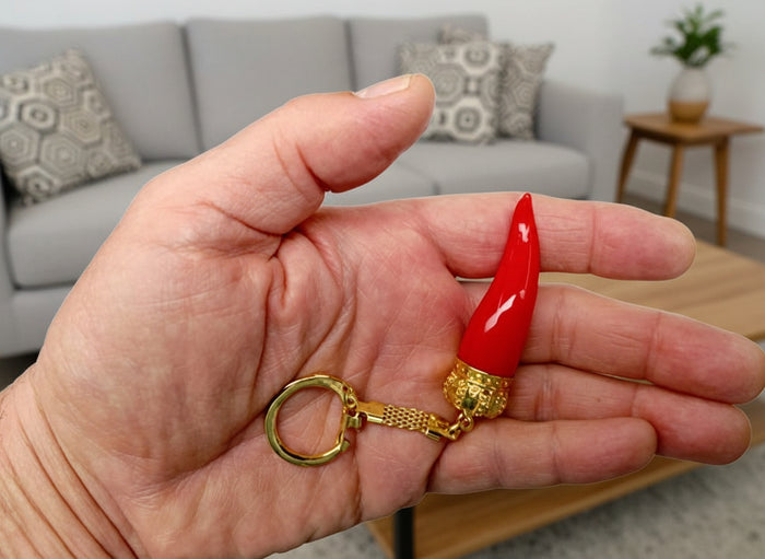 Hand holding a red and gold keychain against a white background