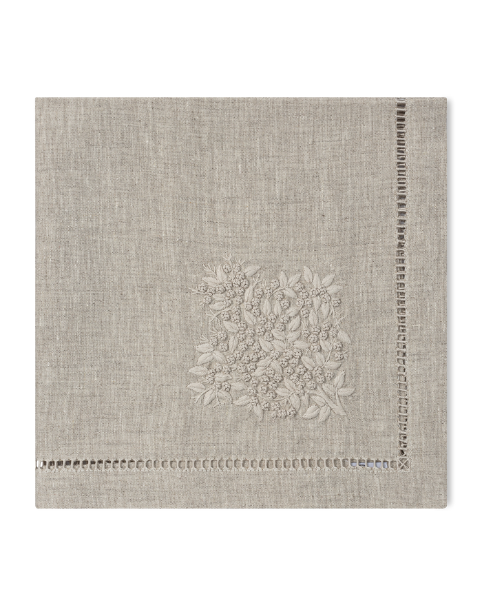 A natural linen napkin with a hemstitch border and natural french knot floral embroidery