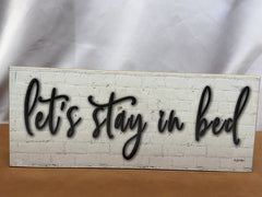 Wood sign reading Let's Stay in Bed